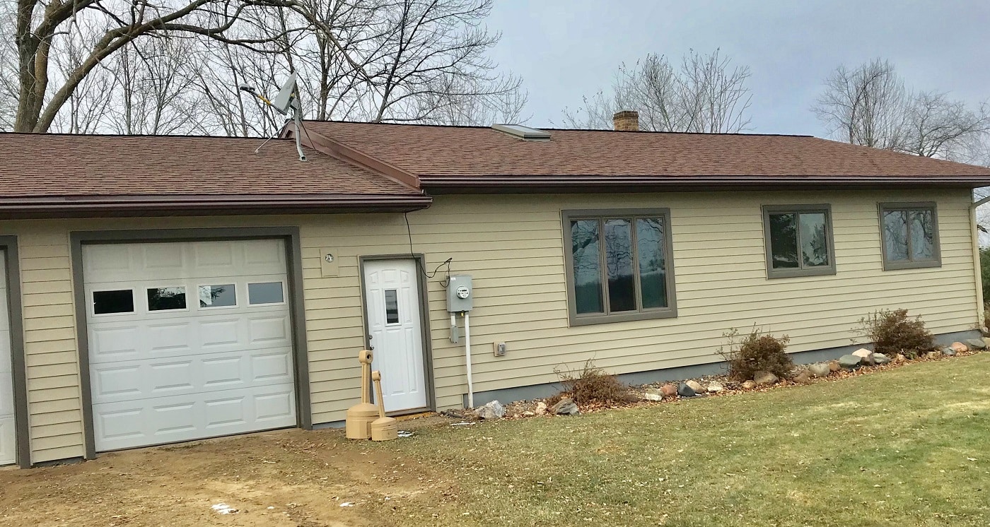 tan steel siding & LeafGuard gutters installed on Downing home