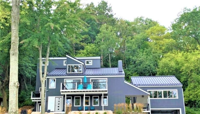 Metal roofing on a modern home surrounded by large trees.
