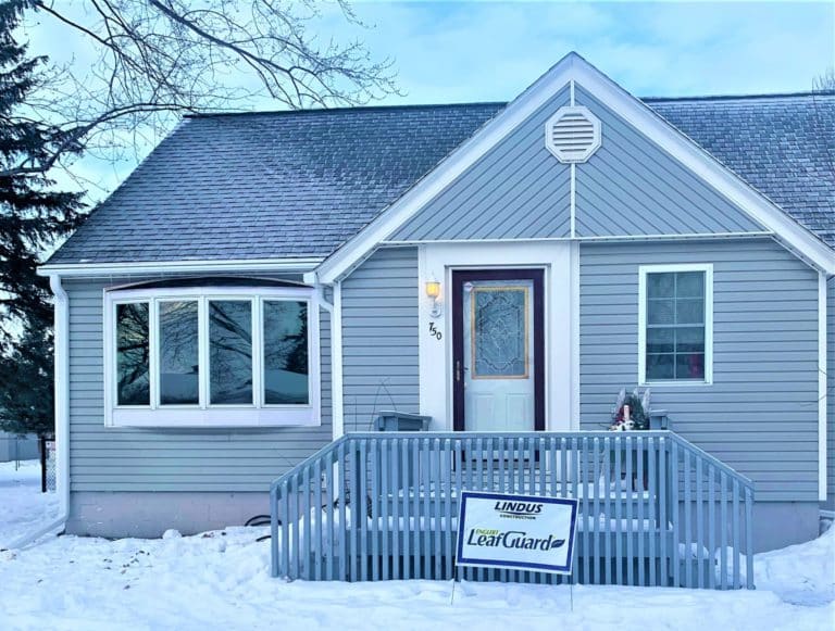 Gutter guards on a small blue house in the winter.