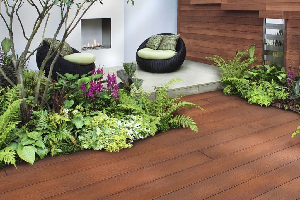 A Millboard deck with plants, two chairs, and an outdoor fireplace.