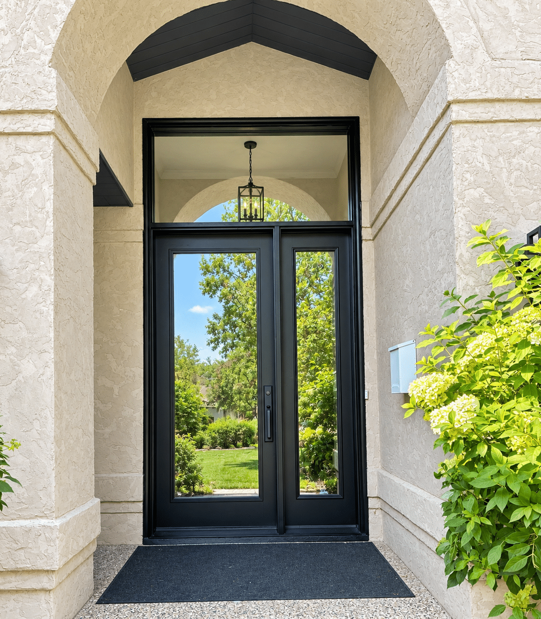Black exterior entry door with glass panels and transom window