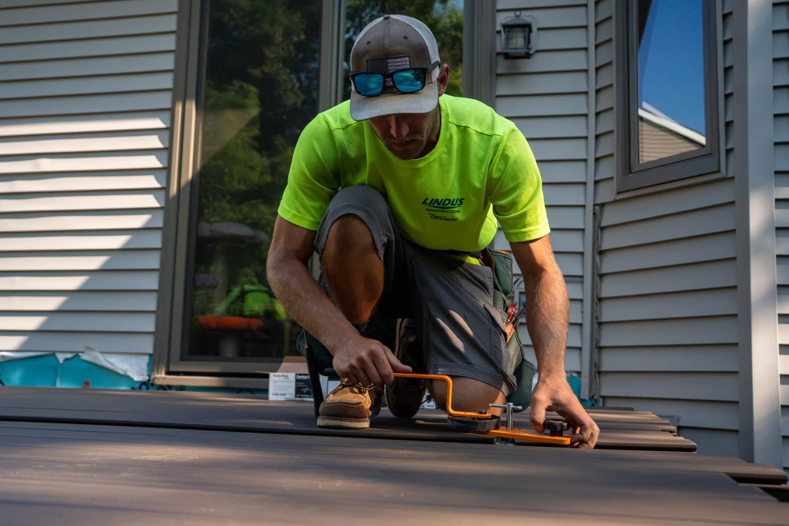 Lindus Construction craftsman installing TimberTech AZEK® decking on a home in Eden Prairie, MN, using a power tool to secure deck boards.