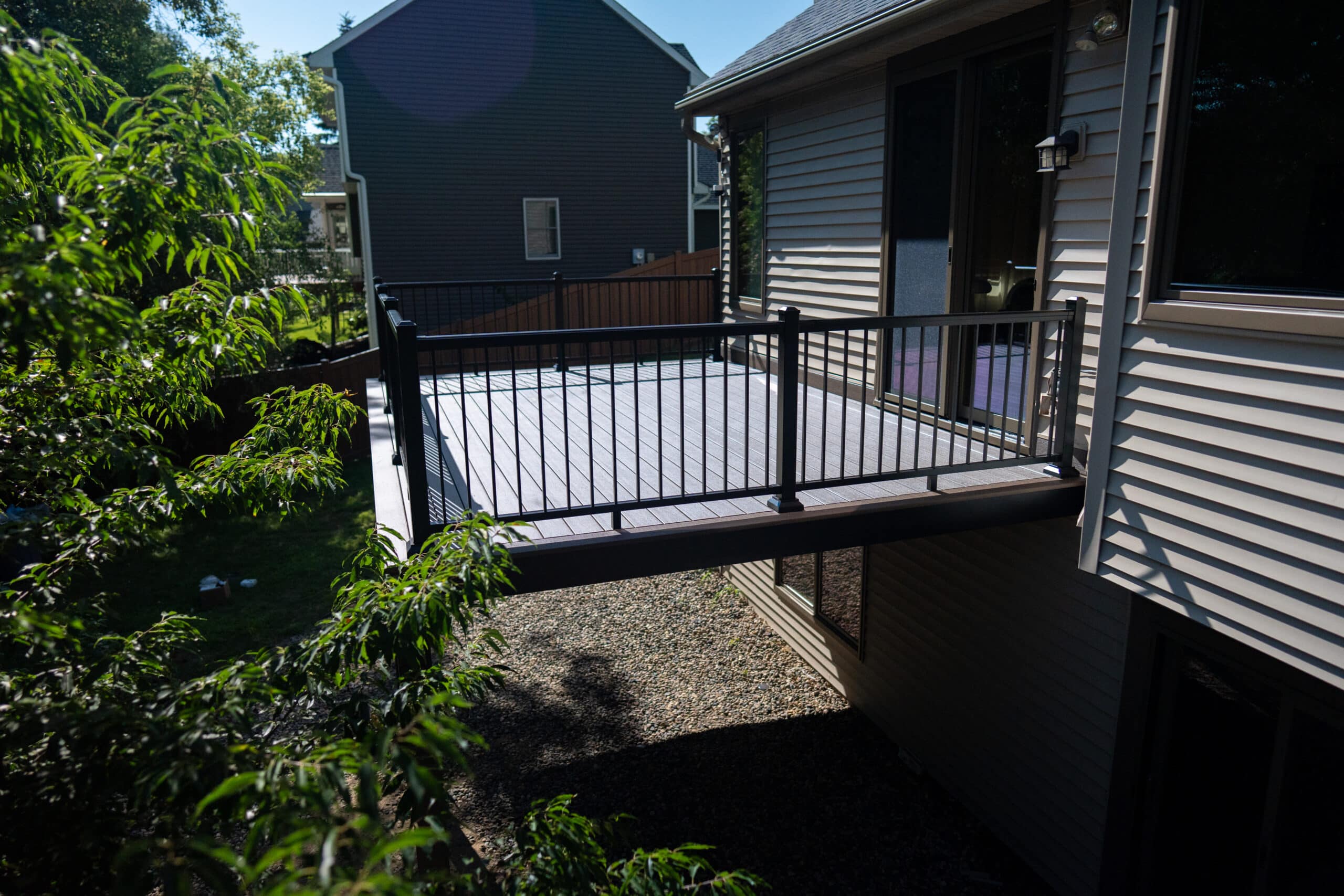 Side view of a completed TimberTech® AZEK® deck featuring black TimberTech® IRX aluminum railings on a home in Eden Prairie, MN.